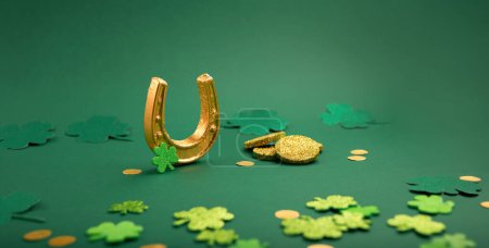 Téléchargez les photos : Carte de jour St Patricks avec symboles traditionnels pour fête irlandaise. Fer à cheval doré, pièces d'or, feuilles de trèfle, trèfles verts sur fond vert, espace de copie. Concept de célébration de la Saint-Patrick. - en image libre de droit