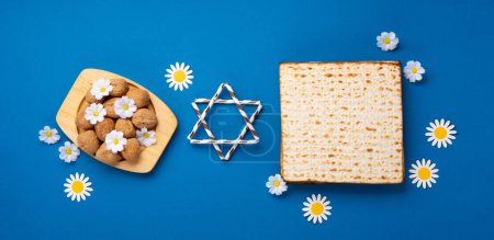 Photo for Jewish holiday Passover greeting card concept. Matzah, nuts, spring flowers on blue table. Seder Pesach spring holiday background, top view, copy space. - Royalty Free Image