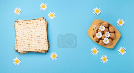 Téléchargez les photos : Juive fête Pâque concept de carte de vœux. Matzah, noix, fleurs de printemps sur table bleue. Seder Pessah printemps fond de vacances, vue de dessus, espace de copie. - en image libre de droit