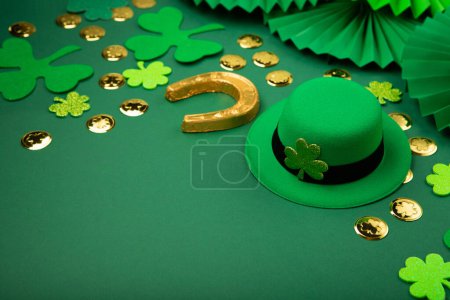 Photo for St. Patrick's Day leprechaun hat, gold coins and shamrocks on green background. Irish traditional holiday concept, copy space. - Royalty Free Image