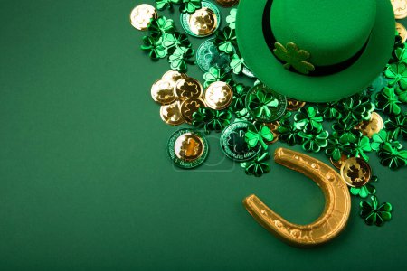 Téléchargez les photos : Chapeau de lutin de la Saint-Patrick, pièces d'or et trèfles sur fond vert. Concept de vacances traditionnel irlandais, espace de copie. - en image libre de droit
