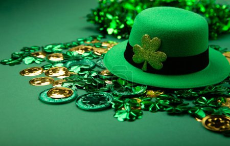 Photo for St. Patrick's Day leprechaun hat, gold coins and shamrocks on green background. Irish traditional holiday concept, copy space. - Royalty Free Image