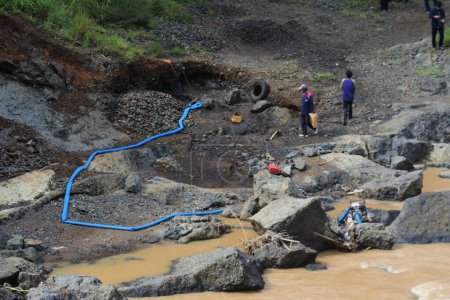 Téléchargez les photos : Two men pick up sand from the river and put it on the outskirts of the river, Sukabumi, Indonesia, May 12, 2022. sand mining on the river. - en image libre de droit