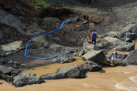 Photo for Two men pick up sand from the river and put it on the outskirts of the river, Sukabumi, Indonesia, May 12, 2022. sand mining on the river. - Royalty Free Image