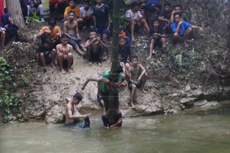 Photo pour Central java, Indonesia -June 10, 2022: Panjat Pinang Greasy Pole over the river. Indonesian People Celebrating the earth's alms after the harvest (sedekah bumi) - image libre de droit