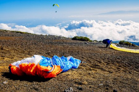 Téléchargez les photos : Les parapentistes glissent dans les airs en se lançant depuis les hautes montagnes avec des parachutes spéciaux. - en image libre de droit