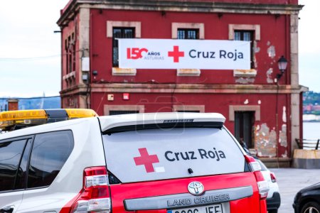 Foto de Oviedo, España - 30 de marzo de 2024: Un vehículo rojo de emergencia estacionado frente a la sede de la Cruz Roja Española. - Imagen libre de derechos