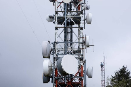 Foto de La torre se mantiene alta con numerosas antenas conectadas a ella, sirviendo como un centro para las señales de comunicación y la transmisión de datos. Las antenas sobresalen en varias direcciones, extendiendo el alcance de las redes inalámbricas y las capacidades de transmisión. - Imagen libre de derechos