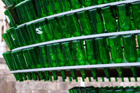 Téléchargez les photos : Plusieurs bouteilles en verre vert sont soigneusement empilées sur une étagère, probablement en attente de recyclage industriel ou de réutilisation. Les bouteilles sont debout, créant un affichage uniforme et ordonné. - en image libre de droit