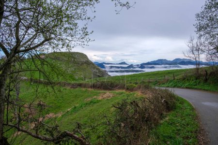 sinuoso camino que atraviesa las montañas de Asturias cubiertas de niebla en España. El camino gira y gira a lo largo del terreno accidentado, ofreciendo un viaje desafiante para los automovilistas.