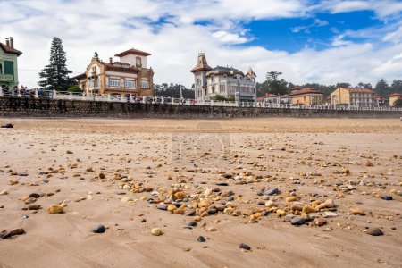 Foto de Una playa de arena en Ribadesella, Asturias, España, está llena de numerosas rocas de diferentes tamaños. Las rocas crean un interesante contraste contra la arena de color claro, agregando textura al paisaje costero. - Imagen libre de derechos