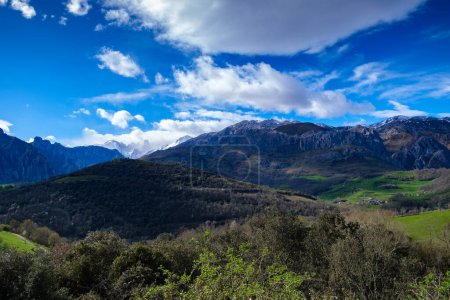 Foto de La imponente montaña Urriellu en medio de valles vastos en la cordillera de los Picos de Europa. El terreno accidentado está lleno de exuberante vegetación, acantilados rocosos y ríos sinuosos, creando un panorama natural impresionante. - Imagen libre de derechos