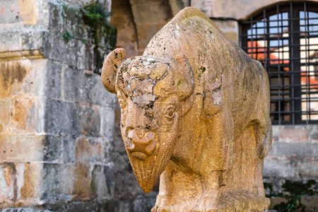 A stone statue of a bull stands prominently in front of a historic building in the medieval city of Santillana del Mar. The bull statue exudes strength and power, adding a sense of grandeur to the architectural setting.
