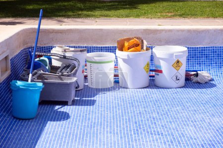 Foto de Múltiples cubos llenos de comida colocados en una piscina de azulejos azules en proceso de reparación y sellado. - Imagen libre de derechos