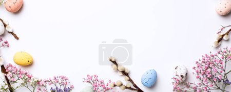 Photo for Beautiful Easter composition with spring flowers and colorful quail eggs over white background. Springtime and Easter holiday banner concept with copy space. Top view - Royalty Free Image