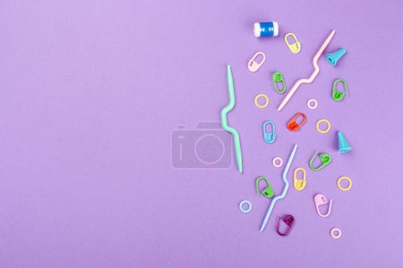 Background with colorful crochet and knitting tools and accesories ober purple. Overhead shot, top view with copy space