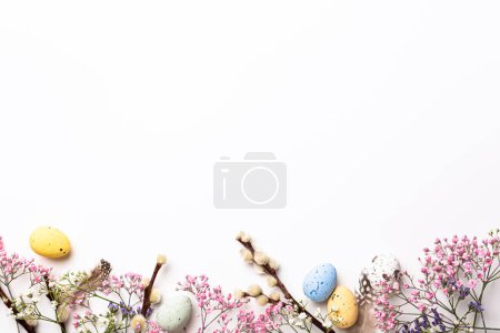 Photo for Easter composition with spring flowers and colorful quail eggs over white background. Springtime and Easter holiday concept with copy space. Top view - Royalty Free Image