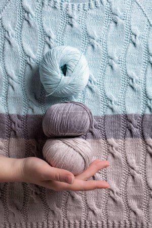 Photo for Unusual Abstract turquoise gray knitted pattern with balls yarn and woman hand background texture. Top view of knitting clothes - Royalty Free Image