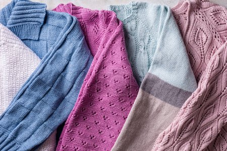 Photo for Overhead view of folded handmade assorted colorful sweater clothing. Homemade colorful knitted clothes background - Royalty Free Image
