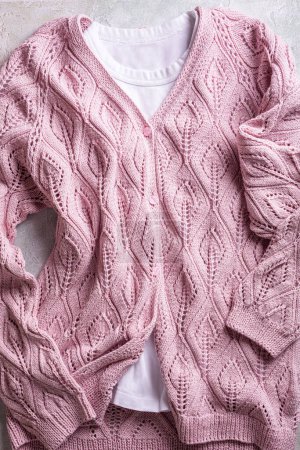 Photo for Pink handmade buttoned long sleeve female cashmere cardigan with knitted leaf shapes and white shirt. Top view. Modern jersey apparel for ladys and girls - Royalty Free Image