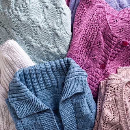 Photo for Overhead view of folded handmade assorted sweater clothing. Homemade colorful knitted clothes background. Modern Sweater Jersey Apparel - Royalty Free Image