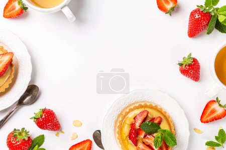 Photo for Beautiful composition of small tartlet pastries with vanilla custard, topped with strawberry fruits and almond sprinkles over white background. Concept of homemade sweet pastries. Copy space, top view - Royalty Free Image