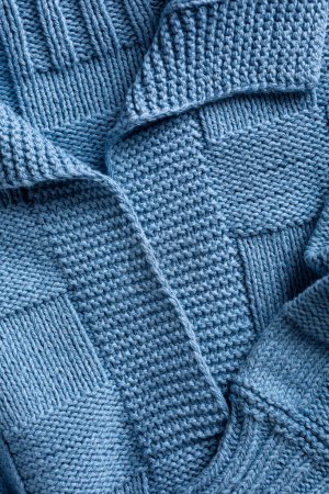 Photo for Close up view of handemade knitted blue women jumper with polo collar. Stylish cotton pullover with chess texture pattern and long sleeves front view. Above shot - Royalty Free Image