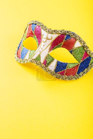 Photo for Vibrant image of a colorful masquerade mask adorned with intricate designs, placed against a bright yellow background. The mask is decorated with glittering patterns. Copy space. - Royalty Free Image