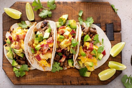 Photo for Breakfast tacos with sausage, scrambled eggs, crumbled bacon and diced avocado, overhead shot - Royalty Free Image