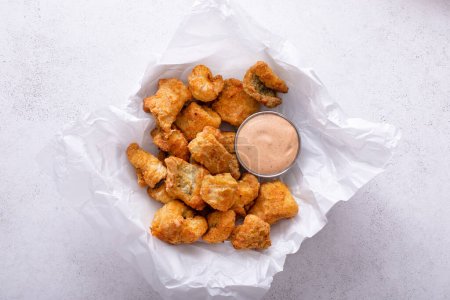Nuggets de poisson-chat frit servis avec de la sauce remoulade sur une assiette avec du papier parchemin