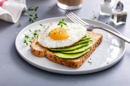 Tostada de aguacate integral con huevo frito en la parte superior, idea de desayuno saludable