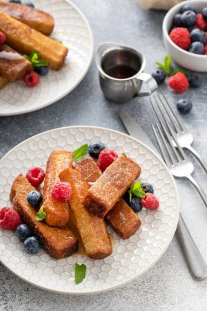 Foto de Palitos de pan francés servidos con bayas frescas y jarabe de arce, idea de desayuno - Imagen libre de derechos