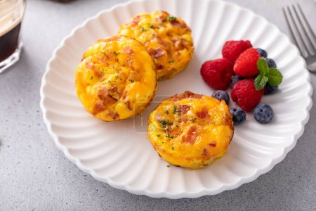 Photo for Breakfast egg muffins or egg bites with potato, bacon and cheddar served with fresh berries - Royalty Free Image