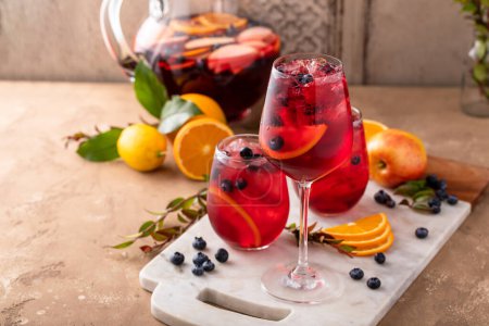 Téléchargez les photos : Sangria rafraîchissante aux baies d'été aux pommes, aux oranges et aux bleuets dans des verres à vin glacés - en image libre de droit