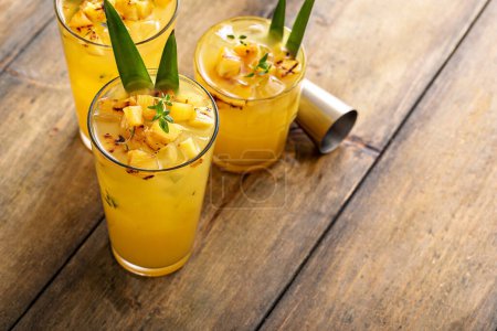 Photo for Grilled pineapple cocktail or mocktail in tall glasses garnished with pineapple leaves, refreshing summer drink idea - Royalty Free Image