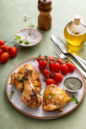 Foto de Tambores y muslos de pollo asados con limón y hierbas servidos con salsa de pesto - Imagen libre de derechos