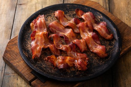 Photo for Cooked bacon on a wooden serving plate, ready to eat breakfast staple - Royalty Free Image