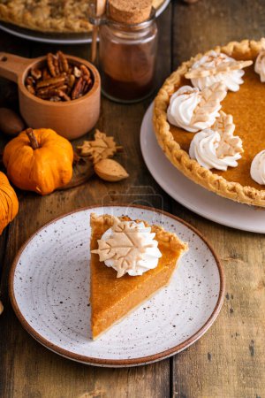 Traditional pumpkin pie for Thanksgiving topped with whipped cream with a slice taken out