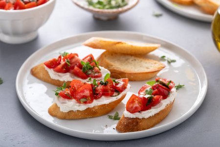 Tomato basil and cream cheese bruschettas with fresh cherry tomatoes and herbs