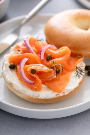 Foto de Panecillo llano con salmón y queso crema con eneldo fresco y alcaparras para el desayuno - Imagen libre de derechos