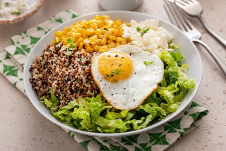 Photo for Breakfast bowl with quinoa, herbed corn, feta cheese and fried egg on top - Royalty Free Image