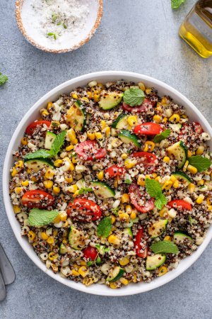Photo for Warm quinoa salad with tomatoes, corn and zucchini with fresh mint and herbs, overhead shot - Royalty Free Image