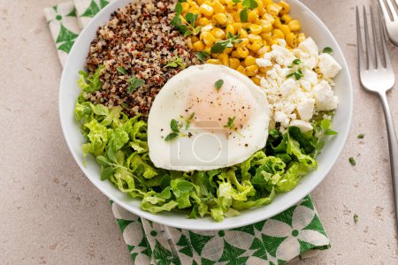 Breakfast bowl with quinoa, herbed corn, feta cheese and fried egg on top