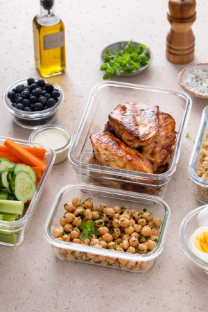 High protein healthy lunch meal prep in containers with chicken, quinoa, herbed chickpeas, vegetables and boiled eggs