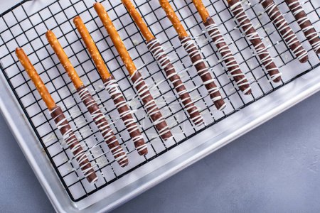 Chocolate dipped pretzel rods with dark and white chocolate on a cooling rack