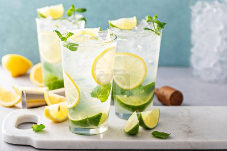 Cold refreshing citrus mojito with lemon and lime and muddled mint in tall glasses