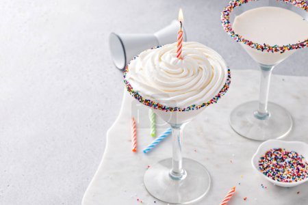 Photo for Birthday cake martini cocktail topped with whipped cream and a birthday candle and sprinkles - Royalty Free Image