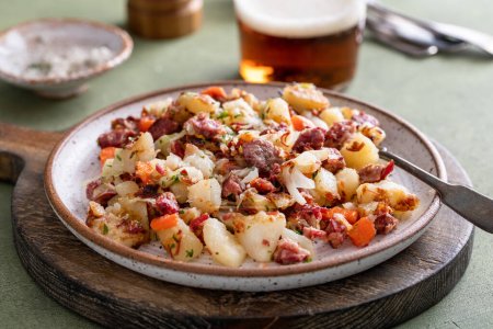 Corned beef hash with potatoes, cabbage and carrots served with beer