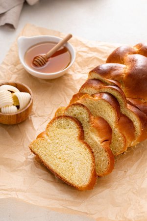 Homemade challah with honey sliced on the table served with butter
