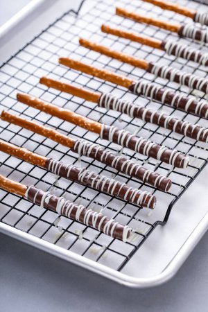 Baguettes de bretzels trempées au chocolat avec chocolat noir et blanc sur un support de refroidissement